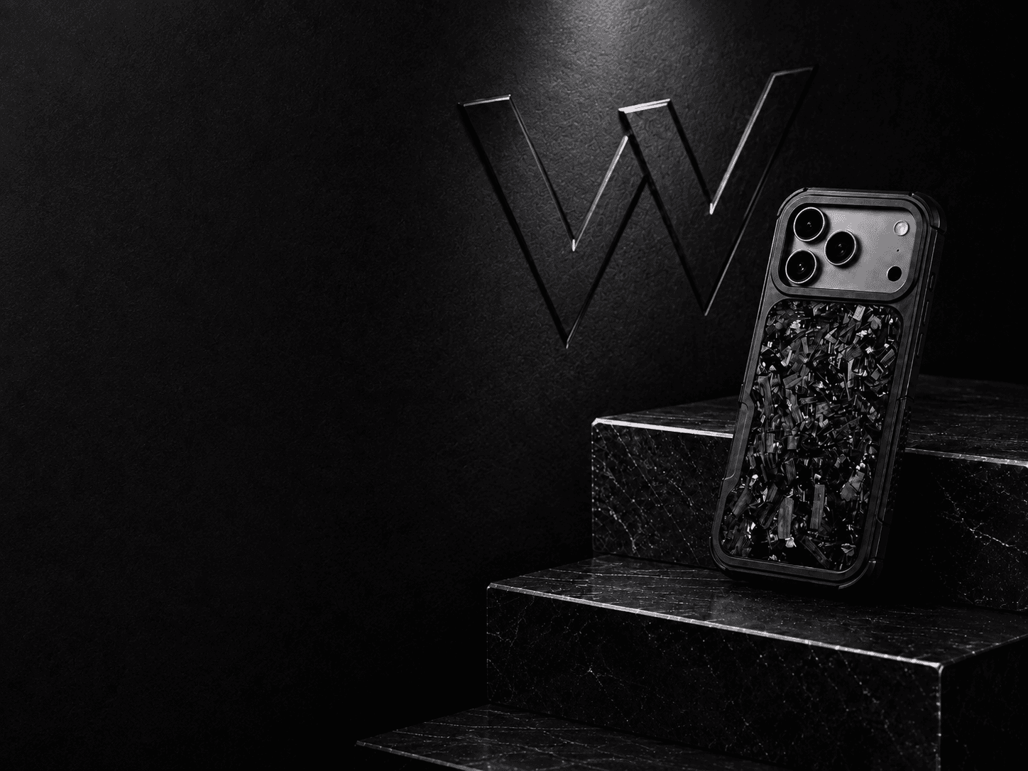 Violet forged carbon WOFT case on black stone beneath a sculpted W